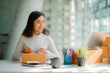 Küçük bir işletme KOBİ işletme sahipleri kurmak, başarılı kadın girişimciler kutularla dizüstü bilgisayarlarla çalışmak ve kutuları hazırlamak için online siparişleri işaretlemek. Müşterilere ve KOBİ iş fikirlerine satış.