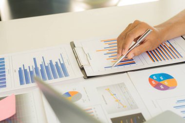 Finansal veri ellerindeki kalemle çalışan iş adamları, masa vergisi konseptinde dizüstü bilgisayar kullanarak yıllık iş raporu analiz raporlarına işaret ediyorlar.