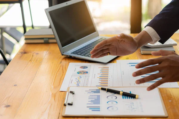 Finansal veri ellerindeki kalemle çalışan iş adamları, masa vergisi konseptinde dizüstü bilgisayar kullanarak yıllık iş raporu analiz raporlarına işaret ediyorlar.