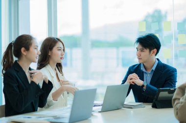 Bir iş yerinde küçük bir grup genç adam modern ofis planlama ve fikir üretme takımında bir araya geliyor. Belgeler ve dizüstü bilgisayarlar üzerinde çalışan bir iş adamının elleri. 