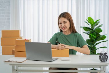 Bağımsız KOBİ Küçük İşletme Girişimcisi Evde dizüstü bilgisayarla çalışan Asyalı bir kadının portresi siparişleri alıyor ve Online Pazarlama Paket Paketleri eTicari iş fikri