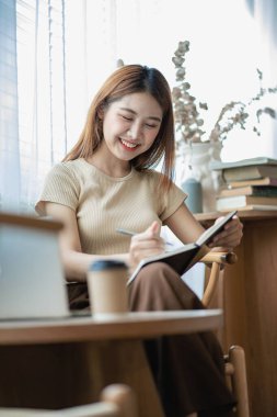 Mutlu gülümseyen Asyalı kadın yatak odasında dizüstü bilgisayar kullanarak rahatlıyor. klavyede çalışan ve daktilo yazan yaratıcı genç kız ev konsepti, dikey görüntü.