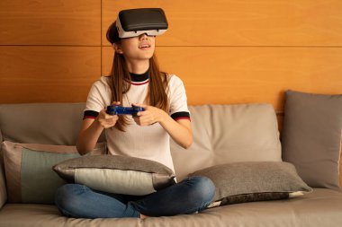 Asian woman using vr glasses, 3D virtual reality headset on SOPA, virtual reality concept, simulation, gaming and technology of the future. Asian women playing games in the room