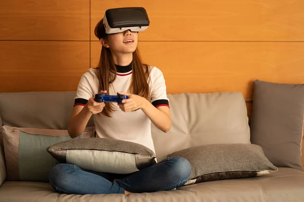 Asian woman using vr glasses, 3D virtual reality headset on SOPA, virtual reality concept, simulation, gaming and technology of the future. Asian women playing games in the room
