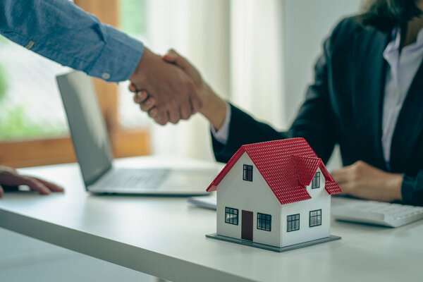 Sales agents and landlords when signing a contract to buy or rent a new home. Real estate agents shake hands with customers after signing contracts. Contract documents and house plans on a wooden table