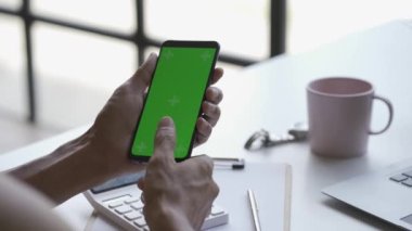 Video 4k. A man holds a smartphone with both hands. Press your finger and slide the green screen chroma button. Click on the application icon, swipe up.