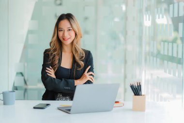 Modern ofiste dizüstü bilgisayarla çalışan Asyalı genç bir iş kadını. gayrımenkul yatırım bilgileri, muhasebe kavramları, finansal sistemler ve vergiler.