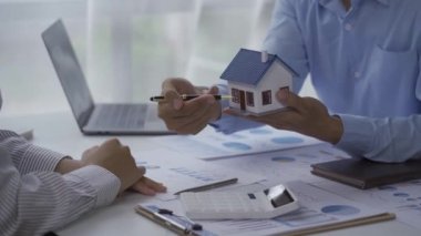 Emlakçılar ve müşteriler sözleşmeleri tartışıyorlar. Ev Mortgage Gayrimenkul Fikirleri İçin Faiz Oranları Satıcısı Mini Ev Modelini Yeni Aile 4k Videosuna Gösteriyor
