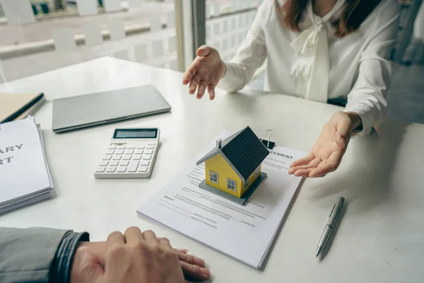 A real estate agent or bank officer explains the interest on a loan to customers with a home sales contract or office loan. Salesperson recommends insurance for customers who buy model homes.