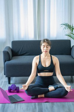Oturma odasında yoga yapan sessiz Asyalı kız yoga ve meditasyon konsepti sabah meditasyonu evde yoga yapan Asyalı kız.