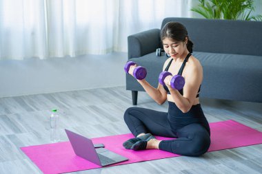 Oturma odasında omuz geren Asyalı kadın yoga yapıyor. Fitness iyi sağlık için uygun yoga..