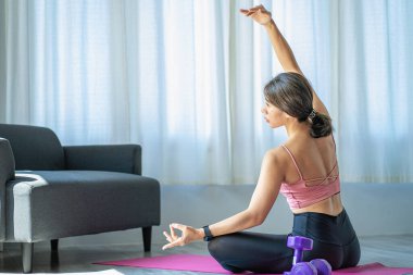 Oturma odasında omuz geren Asyalı kadın yoga yapıyor. Fitness iyi sağlık için uygun yoga..