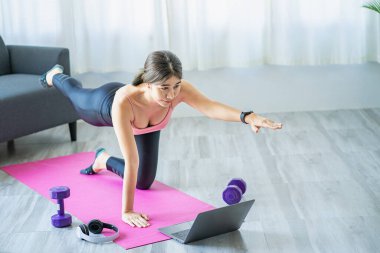 Oturma odasında omuz geren Asyalı kadın yoga yapıyor. Fitness iyi sağlık için uygun yoga..