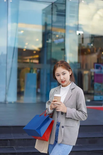 Happy woman with shopping bags enjoying herself after shopping at the festival smiling happily in front of a shopping mall.