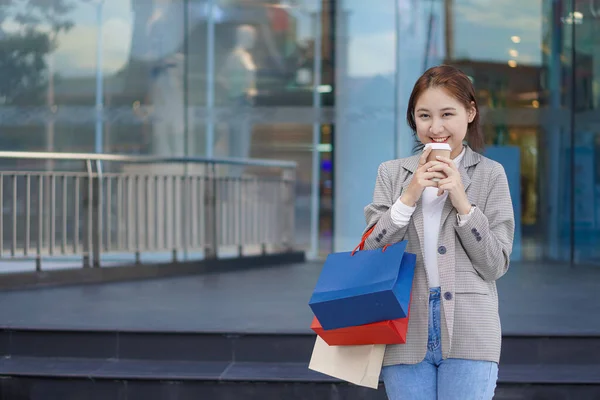 Happy woman with shopping bags enjoying herself after shopping at the festival smiling happily in front of a shopping mall.