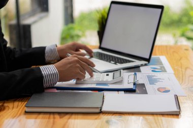 A business accountant or financial professional analyzes business report graphs with a laptop and charts at the company office. and stock market research, concepts, economics, finance