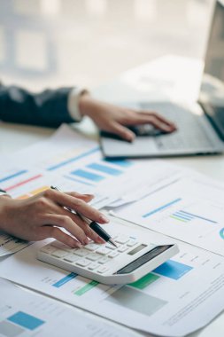 İş adamı elinde çizelgeler, grafikler ve iş stratejileri ile çalışmak için bir kalem tutuyor. Dizüstü bilgisayarlı mali istatistikler masadaki dikey görünümde oturuyor