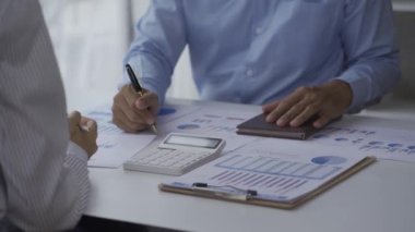 İki iş adamının iş verilerindeki istatistiksel analizi bir dizüstü bilgisayardaki toplantı grafiğinde verileri analiz ediyor. İki iş arkadaşı, 4K çözümü için beyin fırtınası yaparken çok çalışıyor..