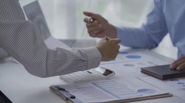 İki iş adamının iş verilerindeki istatistiksel analizi bir dizüstü bilgisayardaki toplantı grafiğinde verileri analiz ediyor. İki iş arkadaşı, 4K çözümü için beyin fırtınası yaparken çok çalışıyor..
