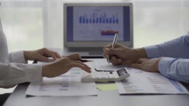 İki iş adamının iş verilerindeki istatistiksel analizi bir dizüstü bilgisayardaki toplantı grafiğinde verileri analiz ediyor. İki iş arkadaşı, 4K çözümü için beyin fırtınası yaparken çok çalışıyor..