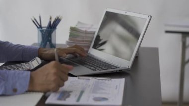 Finansal verileri analiz etmek ve şirket gelişimini göstermek için masa başında çizelgeler ve grafiklerle çalışan bir işadamı. 4k video.