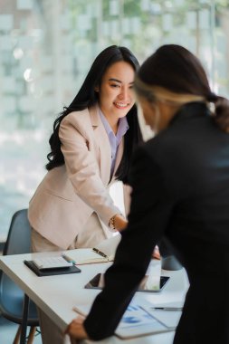 Asyalı kadınlar ve röportajcılar el sıkışıyor. İş adamı, bir ofis konferans odasında iş arkadaşlarıyla masanın etrafında tokalaşırken. karşılama anlaşması konsepti