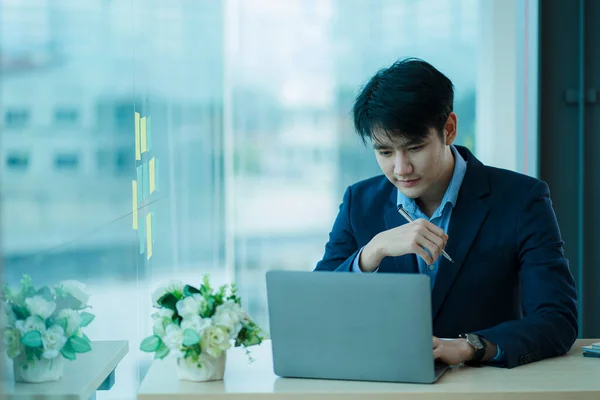 Young Asian businessman video conferencing in a virtual workplace or remote office. Conferencing using intelligent video technology to communicate with colleagues in enterprise businesses.
