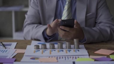 businessman using smartphones in the office he is talking on the phone Through text and working on laptops. Dolly shoots. Daytime. Technology. A financial accounting concept.
