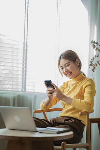 Portrait of an Asian business woman chatting on a smartphone. writing on laptop Laptop in Home Office, Startup, Business, Asia, Women, Online, SME, Telemarketing vertical picture