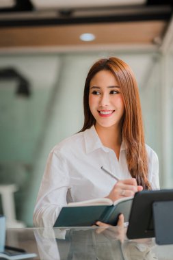 Modern bir ofiste bilgisayar tableti üzerinde çalışan serbest çalışan Asyalı bir kadın. Gayrimenkul yatırım bilgileri finans sistemi konsepti ve vergi dikey tablosu hakkında bir hesap analizi raporu hazırlamak