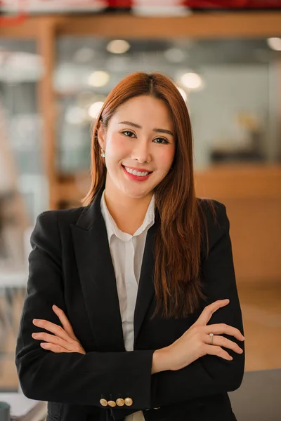 Successful Asian businesswoman smiling happily working on documents in the office vertical picture