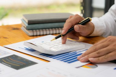 Genç Asyalı işadamı gelir ve giderleri, vergileri, faturaları, kredi kartlarını hesaplamak için hesap makinesine baskı yapıyor. Finansal kavramlar.