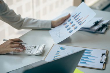 Genç Asyalı işadamı gelir ve giderleri, vergileri, faturaları, kredi kartlarını hesaplamak için hesap makinesine baskı yapıyor. Finansal kavramlar.