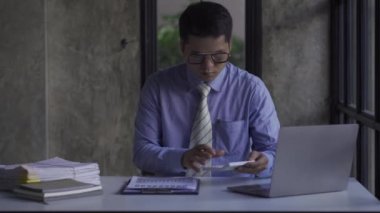 Genç Asyalı işadamı gelir ve giderleri hesaplamak için hesap makinesiyle muhasebe işi yapıyor, vergiler, faturalar, ödeme için kredi kartları ya da evdeki, işyerindeki, finansal konseptlerdeki, 4k video.