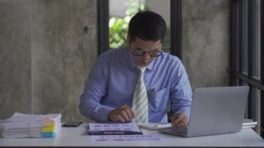 Genç Asyalı işadamı gelir ve giderleri hesaplamak için hesap makinesiyle muhasebe işi yapıyor, vergiler, faturalar, ödeme için kredi kartları ya da evdeki, işyerindeki, finansal konseptlerdeki, 4k video.