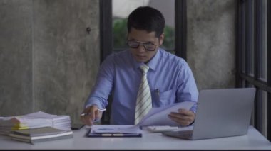 Genç Asyalı işadamı gelir ve giderleri hesaplamak için hesap makinesiyle muhasebe işi yapıyor, vergiler, faturalar, ödeme için kredi kartları ya da evdeki, işyerindeki, finansal konseptlerdeki, 4k video.