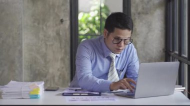 Young Asian businessman doing accounting work with calculator to calculate income and expenses, taxes, bills, credit cards for payment or pay the date at home, at work, financial concepts, 4k video.