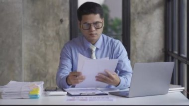 Genç Asyalı işadamı gelir ve giderleri hesaplamak için hesap makinesiyle muhasebe işi yapıyor, vergiler, faturalar, ödeme için kredi kartları ya da evdeki, işyerindeki, finansal konseptlerdeki, 4k video.