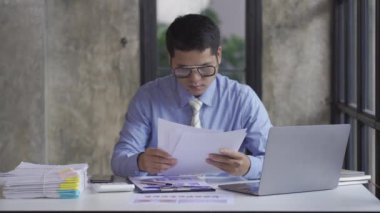 Young Asian businessman doing accounting work with calculator to calculate income and expenses, taxes, bills, credit cards for payment or pay the date at home, at work, financial concepts, 4k video.