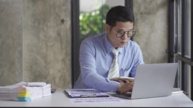 Genç Asyalı işadamı gelir ve giderleri hesaplamak için hesap makinesiyle muhasebe işi yapıyor, vergiler, faturalar, ödeme için kredi kartları ya da evdeki, işyerindeki, finansal konseptlerdeki, 4k video.