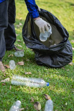 Gönüllüler çöp poşetlerinde plastik şişeler topluyor. Çevre kirliliği, çevre kirliliği, çöplük temizliği, gönüllü toplum çevresi. Aile geliri olarak satılabilecek genç samimiyeti geri dönüşümü.