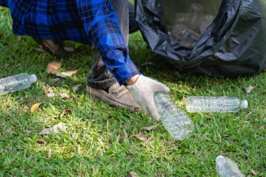 Gönüllüler çöp poşetlerinde plastik şişeler topluyor. Çevre kirliliği, çevre kirliliği, çöplük temizliği, gönüllü toplum çevresi. Aile geliri olarak satılabilecek genç samimiyeti geri dönüşümü.