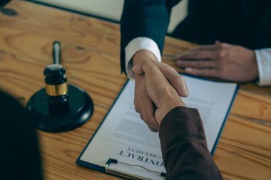 Businessmen shake hands after consulting the law from lawyers, judges, and legal counsel. Consulting services on various contracts to plan a court case with hammers and scales next to
