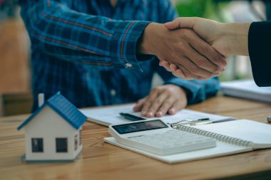 Satış temsilcisi müşteriye mülkü satın alması için bir ev satın alma sözleşmesi sunar, satış temsilcisiyle ev sahibi arasında bir el sıkışma ya da kira sözleşmesi imzalarken..