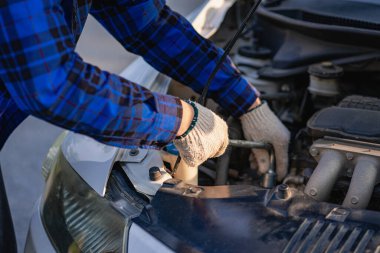 Genç bir adam uzun bir yolculuğa çıkmadan önce arabasını kontrol eder ve tamir eder..