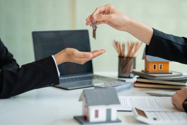 Ev satış temsilcisi iş adamının anahtarlarını tutuyor. Ajan anahtarı müşteriye veriyor. Ev Alım ve Sigorta Fikirleri