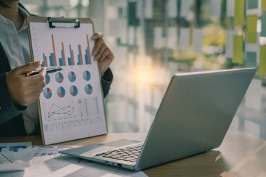 Businessman holding documents containing financial statistics, stock photos, discussion and data analysis, charts and graphs, charts, diagrams, business, and work concepts.