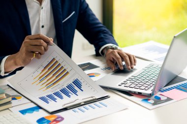 Finansal istatistikler, stok fotoğrafları, tartışma ve veri analizleri, grafikler, şemalar, şemalar, iş yerleri ve iş kavramlarını içeren belgeleri elinde tutan işadamı.