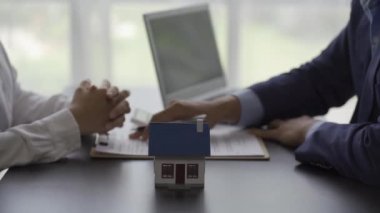 Emlakçı projedeki konutun modelini müşteriye ayrıntılı olarak açıklamak ve konut ve kredi alımları hakkında bilgi vermek için açıklar. 4k video yanında ev tasarımları ile