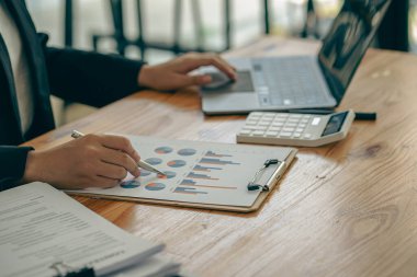 Elinde kalem ve kağıt tutmakta olan işadamı, ofis kavramı muhasebesinde dizüstü bilgisayar kullanarak yıllık iş raporunu hesaplıyor.